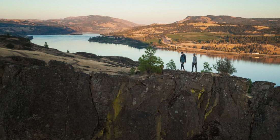 People outdoors hiking on a ridge above a riverbank.