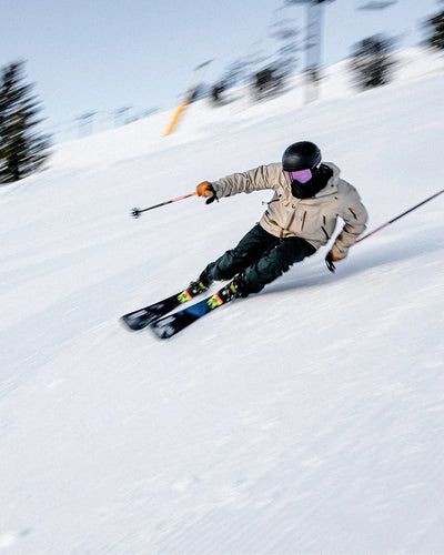 Person skiing down a snowy slope with ski poles and a helmet.