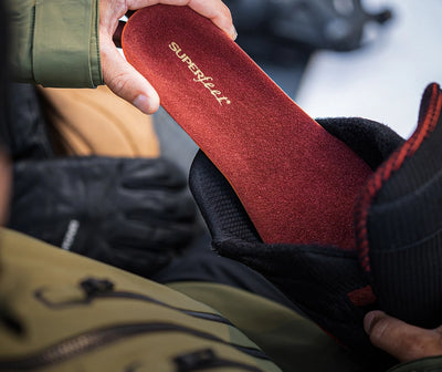 A close up shot of a person inserting Superfeet's Winter Support Insole into a boot. 